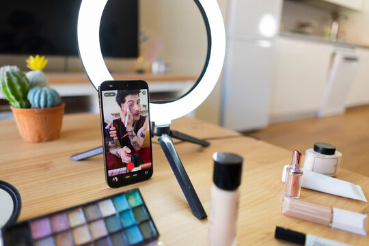 Person creating online makeup tutorial content with smartphone