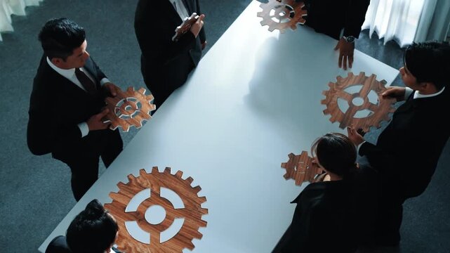 Top view of skilled business people separate wooden cog at meeting. Group of project manager helping and team working tand finding problem at meeting room or workplace. Represent unity. Directorate.