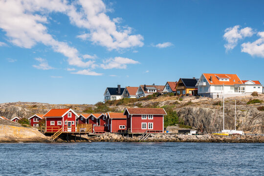 Red wooden fishing huts at waterfront and houses on Rodergatan situated atop the granite rocks of Sm&ouml;gen island near Kungshamn, Bohusl&auml;n, Swedish west coast