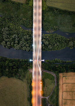 Aerial view of Mary McAleese Boyne Valley Bridge illuminated at dusk over the River Boyne and lush green forests in Drogheda, County Louth, Ireland.