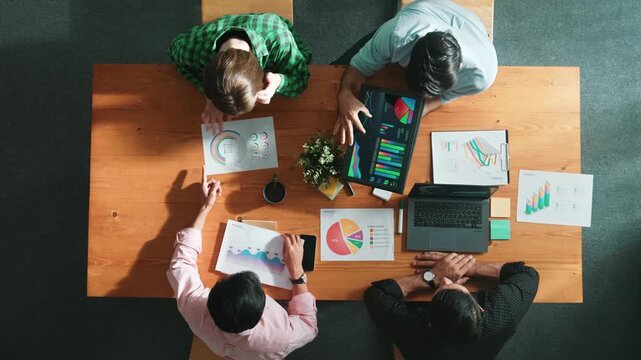 Time lapse of diverse business people working together to analyze chart. Top down aerial view of creative team looking at stock market report and discussing about financial investment. Convocation.