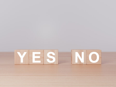 Wooden blocks arranged to spell the words yes and no on a flat wooden surface under soft lighting