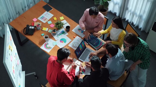 Top view of skilled business team discussing and talking about financial statistic to make decision for investment. Creative project manager looking at data analysis from laptop screen. Convocation.