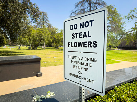 A sign at a cemetery stating Do Not Seal Flowers punishable by fines or jail