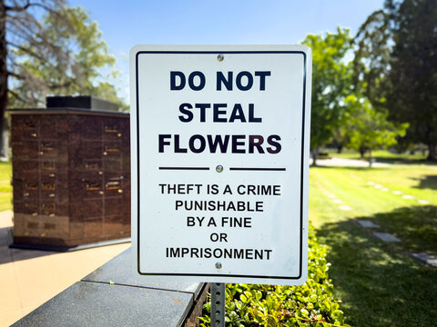 A sign at a cemetery stating Do Not Seal Flowers punishable by fines or jail