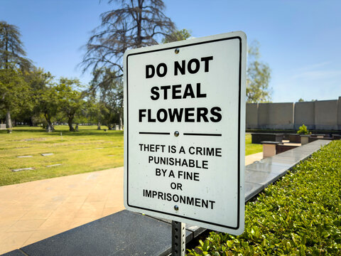 A sign at a cemetery stating Do Not Seal Flowers punishable by fines or jail
