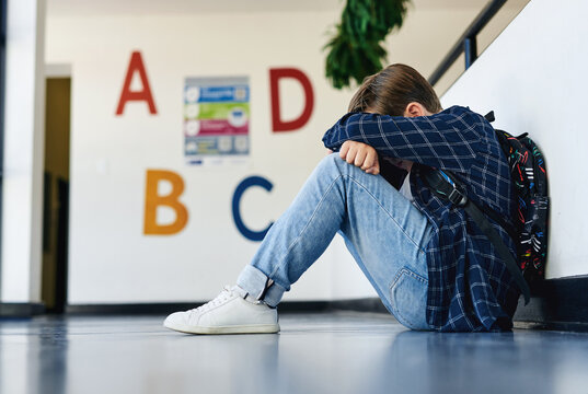 Education, child and sad in classroom hallway for social isolation, bullying or mental health. Stress, unhappy or person with depression at elementary school for exclusion, lonely or learning outcast