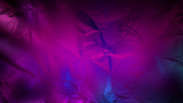 The texture of the crumpled foil is colored with bright highlights, the looped fast animated background is pink and purple.