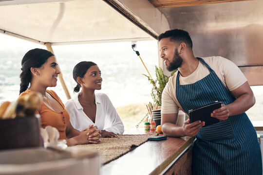 People, talk and customer service at food truck with tablet, menu recommendation or catering startup. Small business owner, women and order at takeaway restaurant with tech, hospitality or discussion