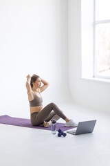 Obraz premium Fit woman doing yoga plank and watching online tutorials on laptop, training in living room