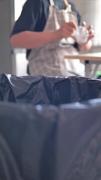 Person placing plastic bottle into recycling bin in a home. Waste sorting, sustainability and environmental responsibility concept