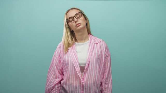 Woman wearing glasses tilts head back with closed eyes in a studio wearing pink striped blouse and white tee; fatigue contemplation.
