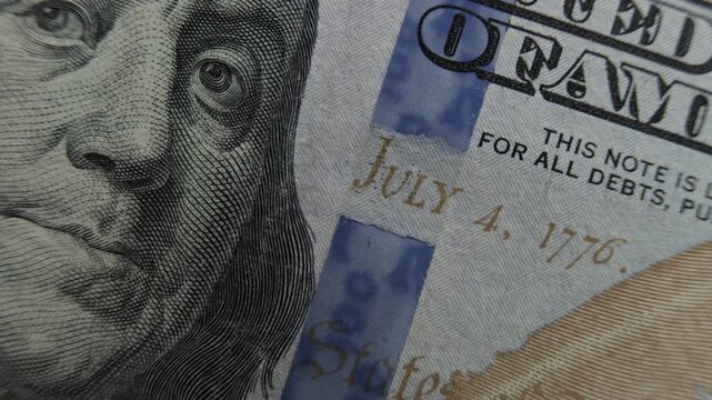 One hundred dollar US bill with portrait of Benjamin Franklin and blue holographic security stripe