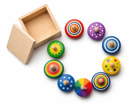 New wooden and colorful spinning tops arranged in a clean flat lay composition with several brightly painted tops displayed in a neat circular pattern and a small open storage box nearby