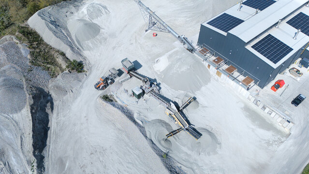 Aerial view of the Foamed Glass Industrial Factory featuring conveyor belts, piles of raw material, and solar panels on the roof in Great Heck, England, United Kingdom.