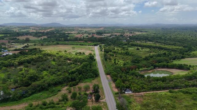 High-angle drone footage of a winding mountain road cutting through dense green forest, capturing natural landscape, scenic travel route, and peaceful countryside environment from above.