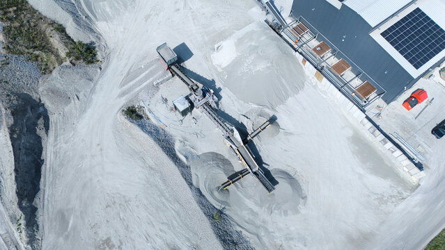 Aerial view of the Foamed Glass Industrial Factory featuring conveyor belts, piles of aggregate material, and solar panels on the roof in Great Heck, England, United Kingdom.