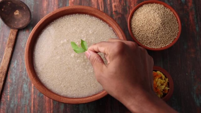Millet porridge in a mud plate on a wooden table. Millet porridge with lentils healthy breakfast or dinner. Diabetes friendly meal. Kanji fox tail millet in Kerala India.
