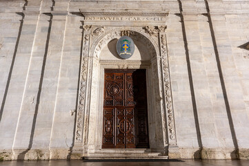 Fototapeta premium Torino, Italia - 12/06/2014 - il Duomo Portale ligneo scolpito con arco in pietra decorato e stemma ecclesiastico. Dettaglio architettonico ideale per temi arte sacra, storia, cultura.