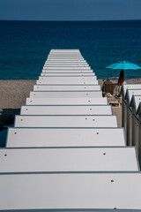 Fototapeta premium Scale bianche che portano al mare con ombrellone blu e lettini