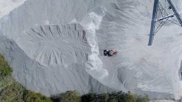 Aerial view of Foamed Glass Industrial Factory with a bulldozer moving large piles of grey aggregate in Great Heck, England, United Kingdom.