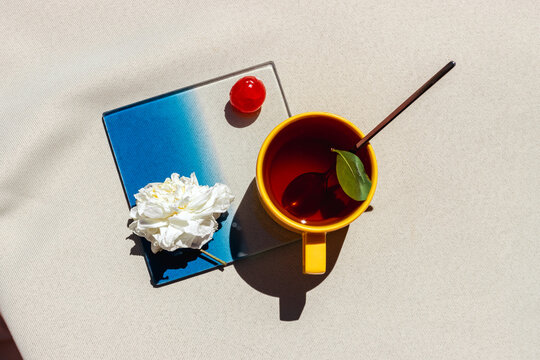 Minimal still life with yellow mug and white flower directly above