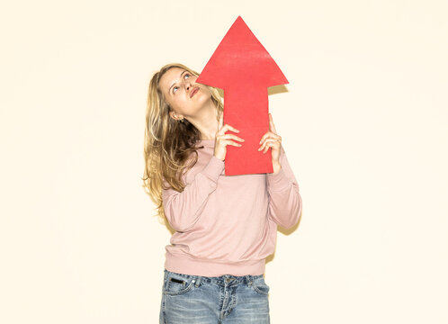 Woman holding red paper arrow pointing upward to show direction