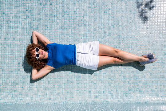 Relaxing model in an empty blue tiled swimming pool in Granada Spain