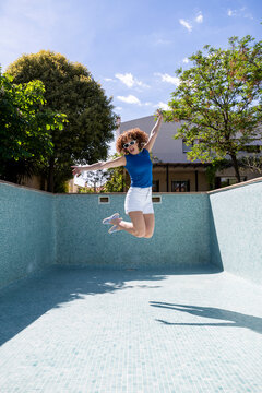 Model jumping mid-air in an empty swimming pool during summer
