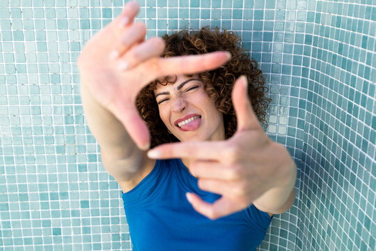 Cheerful model framing with hands outdoors in empty blue pool