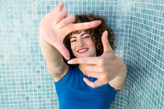 Smiling model framing with hands in an empty pool during summer