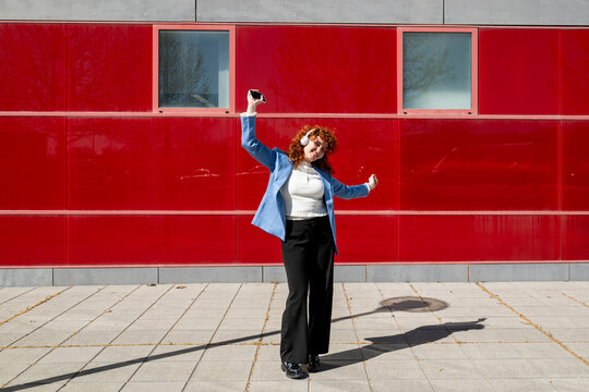Entrepreneur dancing with smartphone against red background