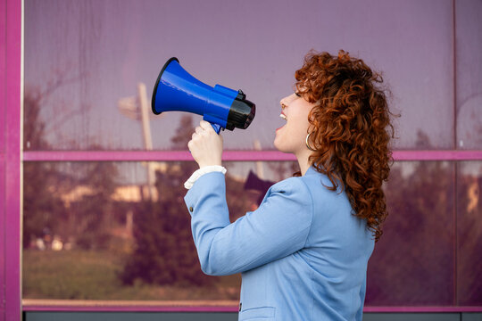 Entrepreneur in blue blazer shouting through megaphone outdoors