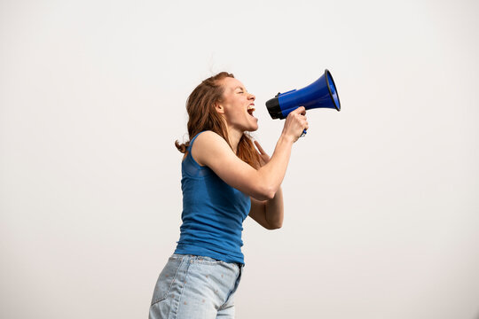 Activist in blue shirt shouting through megaphone outdoors