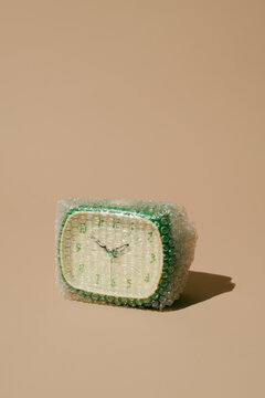 Old green clock wrapped in bubble wrap showing fragile time