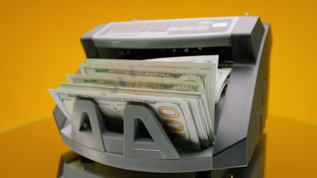 Angled Money Counter Counting Dollars on Yellow
