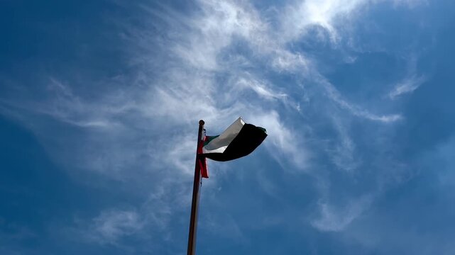 Arab country flag blowing in the wind against a blue sky background