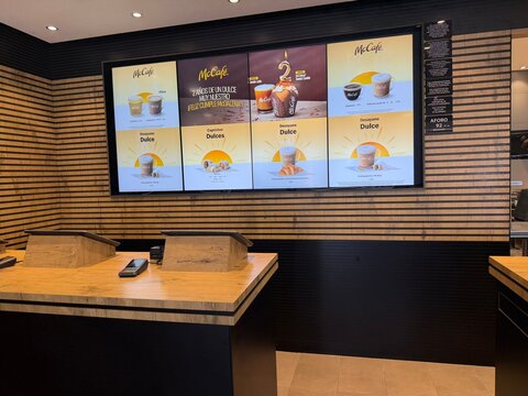 Palma, spain, may 2, 2026, mccafe digital menu board displaying coffee and pastry options in mcdonald's counter area with modern wood paneling