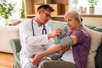 Fototapeta premium An elderly woman undergoes a routine blood pressure check as a doctor carefully operates the monitoring device.