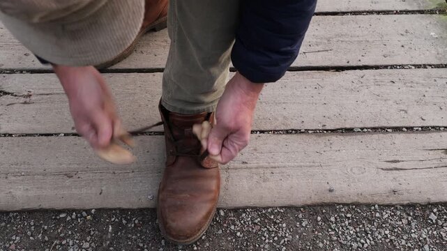 Stockholm, Sweden A man ties his shoelaces on a wooden boardwalk. 