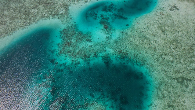 Stunning aerial view of a vibrant turquoise lagoon, crystal-clear ocean water revealing coral reefs, a serene tropical seascape for travel and nature themes