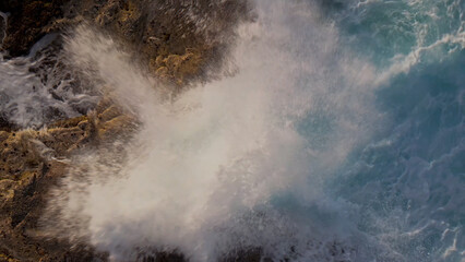 Dynamic ocean waves crashing against rugged brown rocks, powerful sea spray and white foam, a dramatic natural coastal scene, perfect for environmental and travel themes. © Shanza