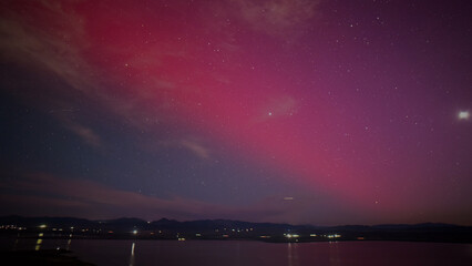 Fototapeta premium Vibrant pink and purple aurora borealis illuminating a dark night sky, stunning natural light phenomenon over a tranquil lake, celestial display for breathtaking backgrounds and atmospheric
