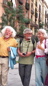 Happy senior friends walking together on a city street. Group of mature tourists exploring a european city, talking and laughing