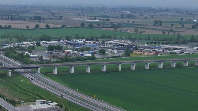 A1 Autostrada del Sole and A21 Torino Piacenza interchange near Fiorenzuola d'Arda Piacenza Emilia Romagna Italy with Autogrill service area and SS9 Via Emilia crossing agricultural Pianura Padana