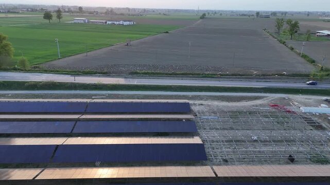 Solar photovoltaic plant under construction near Fiorenzuola d'Arda Po Valley Italy with ground mounted monocrystalline panel arrays mounting structures and earthworks along SS9 Via Emilia