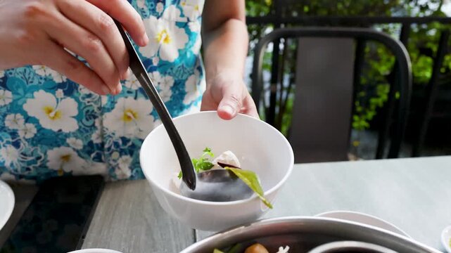 Serving Spicy Thai Tom Yum Soup Into a White Bowl