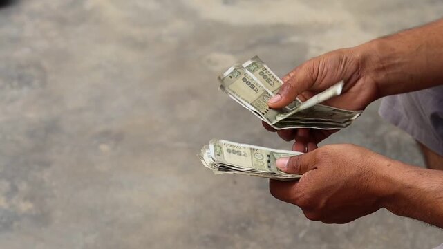Close up of an Indian man counting five hundred rupee notes outdoors, male hands holding and counting Indian currency cash, finance and investment concept
