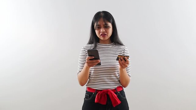 Unhappy Asian Woman hold credit card use phone try to pay through e-bank app experiences problems due insufficient funds, no money, insecure online payment, fraud, unsuccessful transaction concept