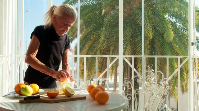 Senior Woman Squeezing Fresh Citrus Juice on Sunny Balcony in San Remo Italy